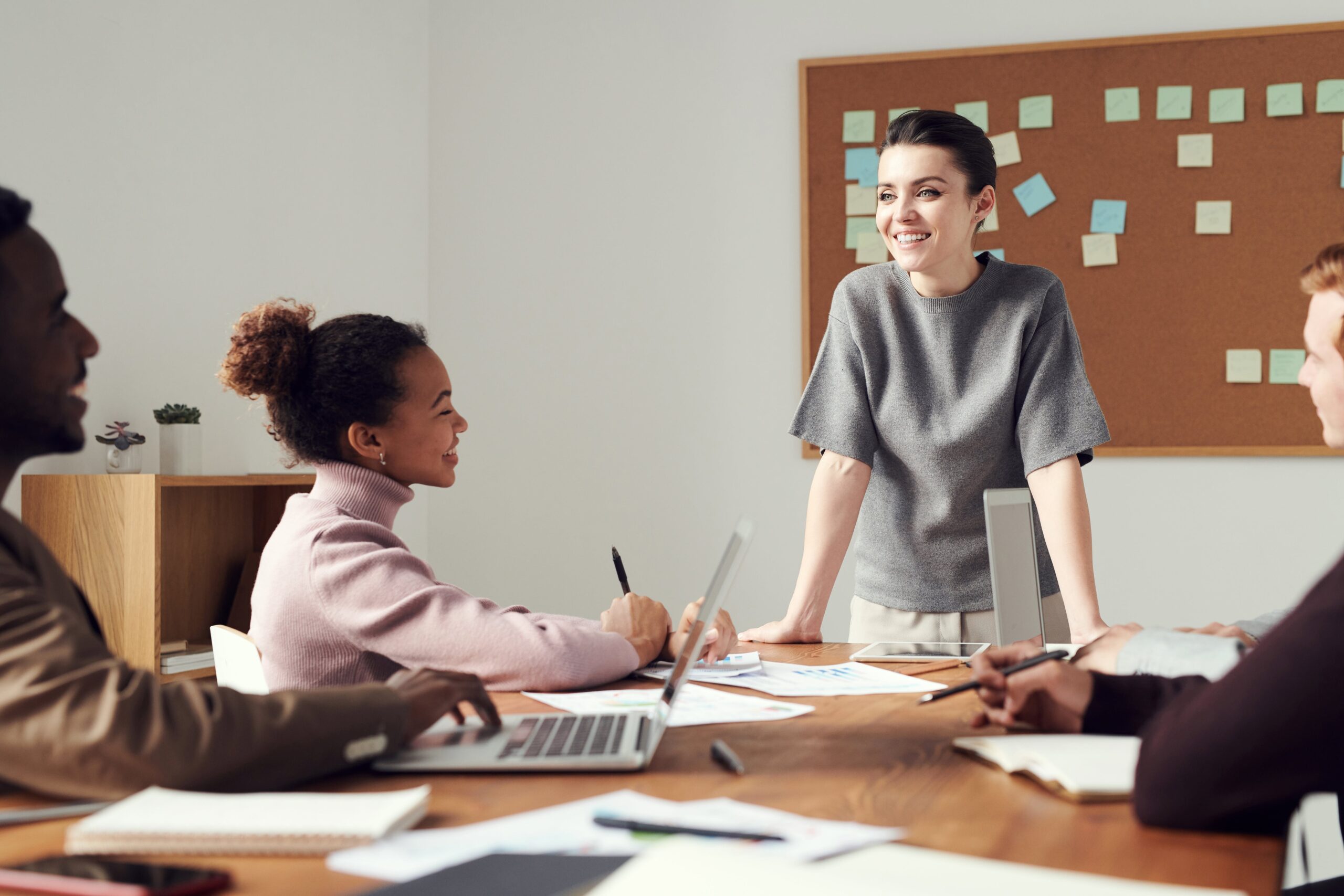Employee Pulse Surveys | Woman Talking To Co Workers At Desk