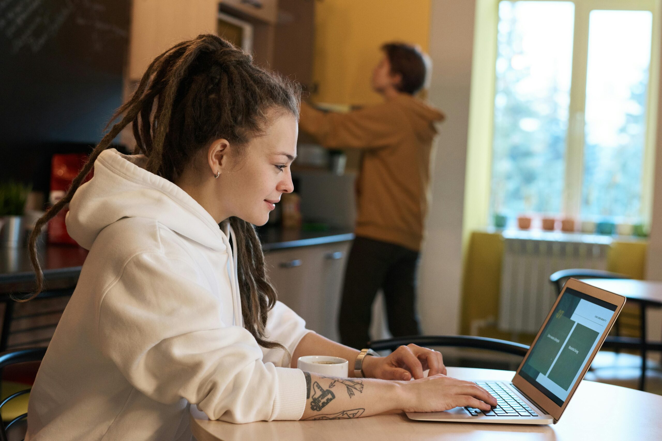 Young woman in hoodie at desk completing engagement survey on laptop
