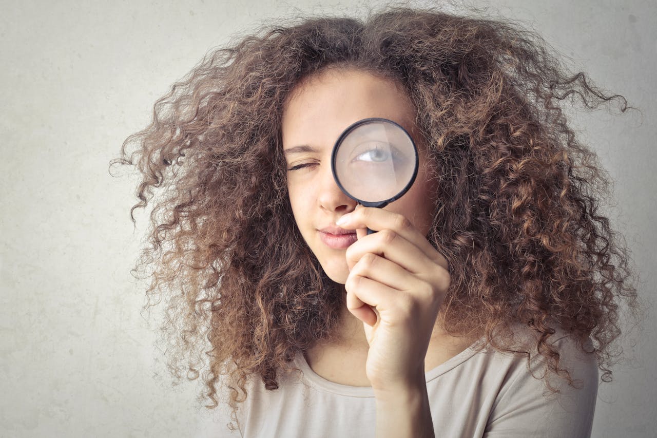 a woman holding a magnifying glass over her eye
